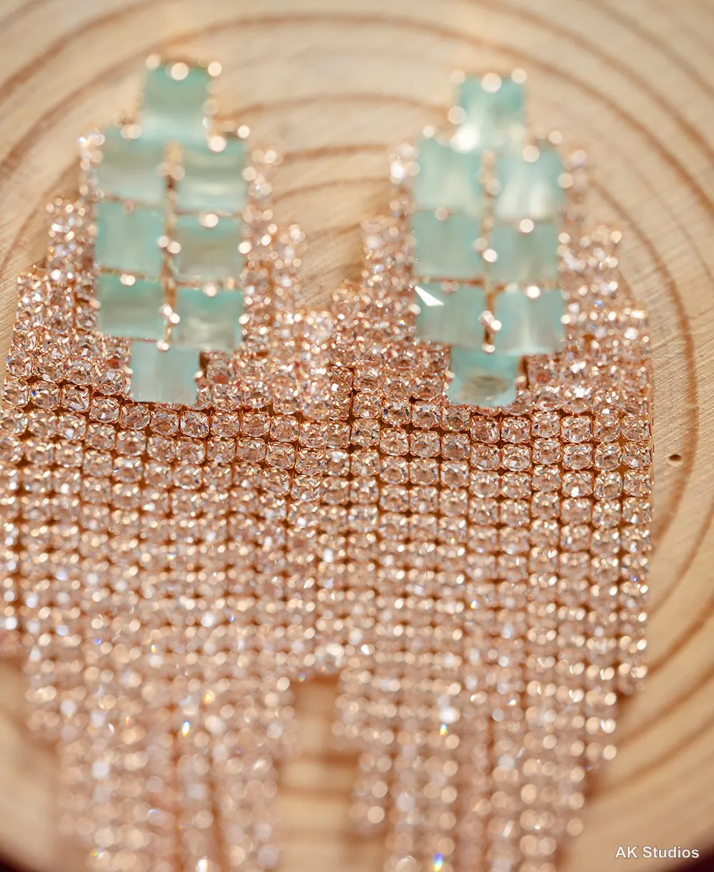 Macro close-up of rose gold rhinestone fringe earrings showing individually lit crystal facets