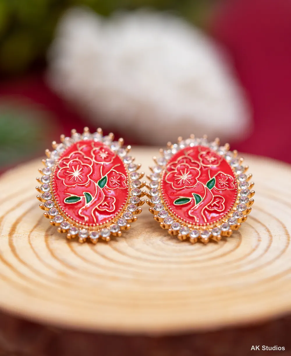 Red enamel floral stud earrings with a crystal halo, photographed with macro product lighting